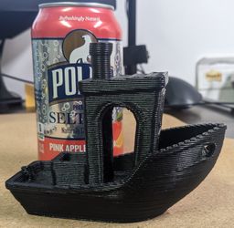 The large 3D-printed tugboat model on a desk, next to a drink can.